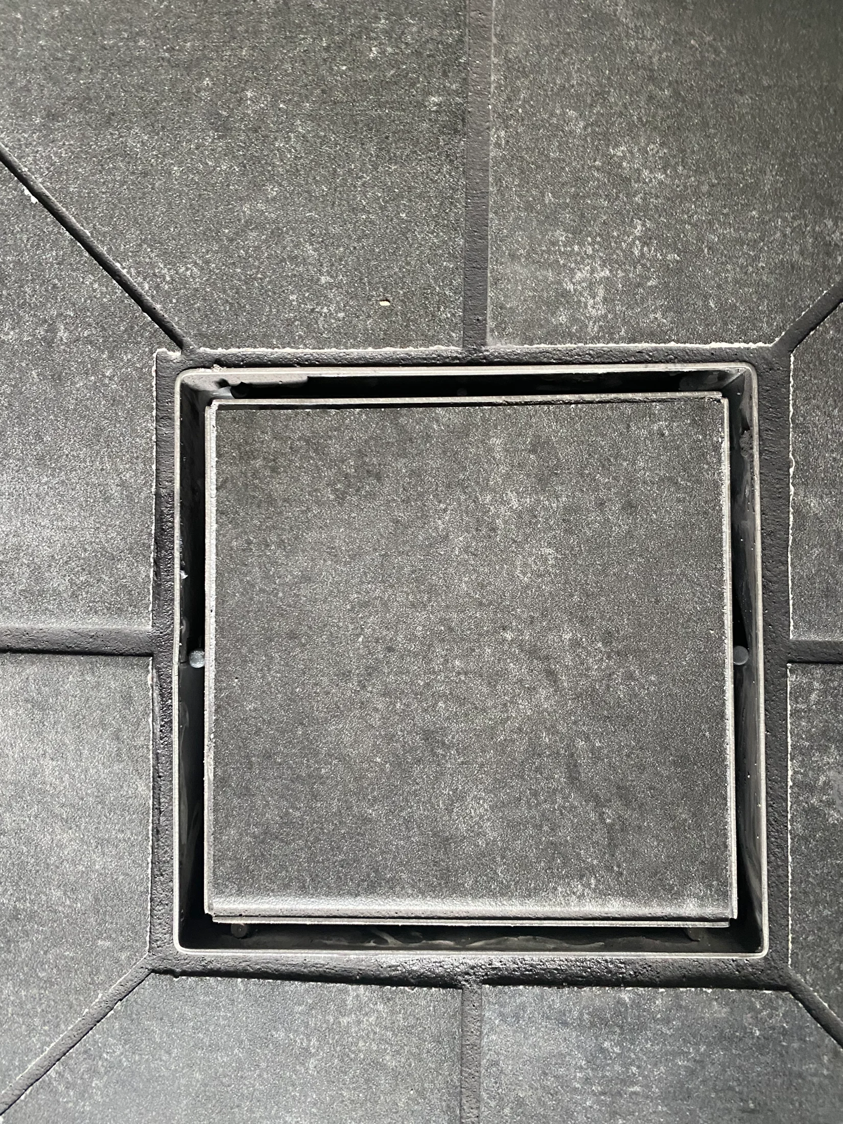A tile grate with lipped and poorly cut tiles surrounding it