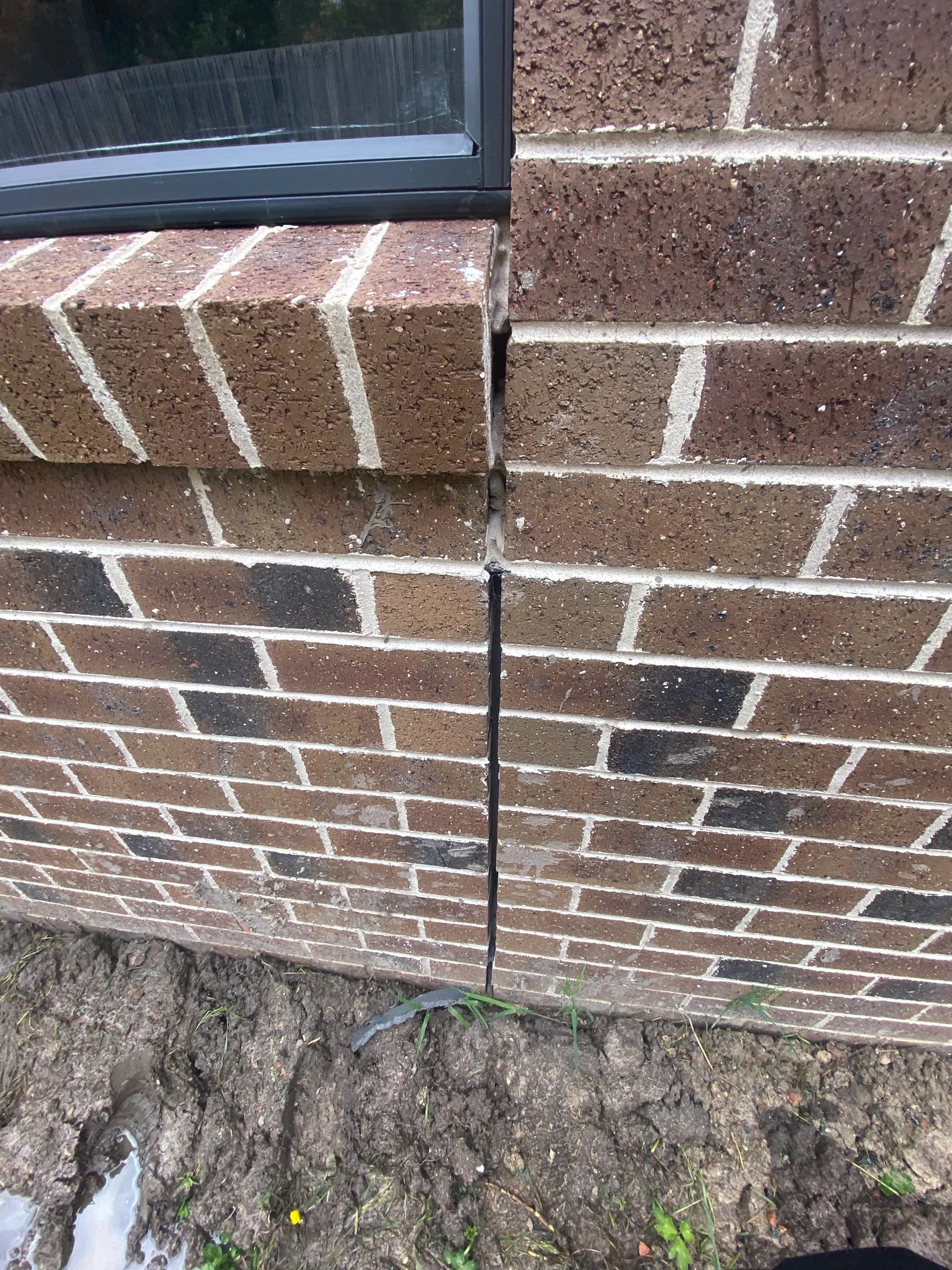A picture of an articulation joint in new brickwork, covered with oversprayed concrete, poorly done.