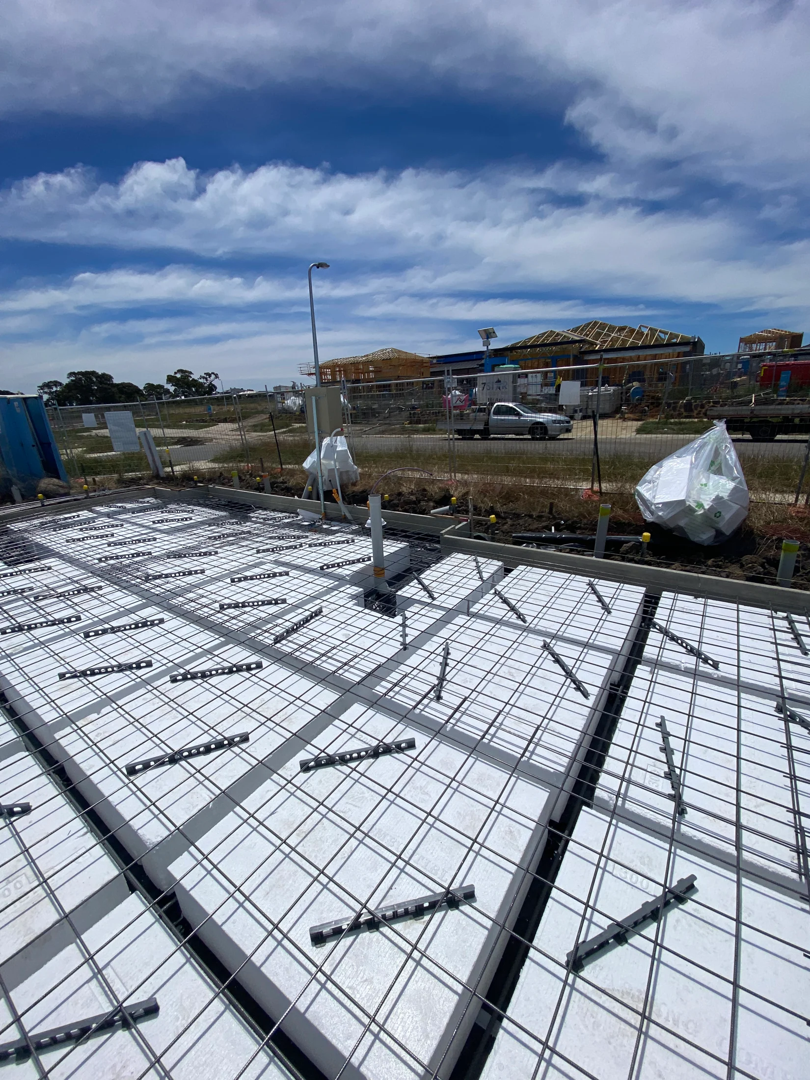 A concrete slab of a new home build set up, proper to pouring of the concrete with formwork, waffle pods, reinforcement and temporary fencing viewable.