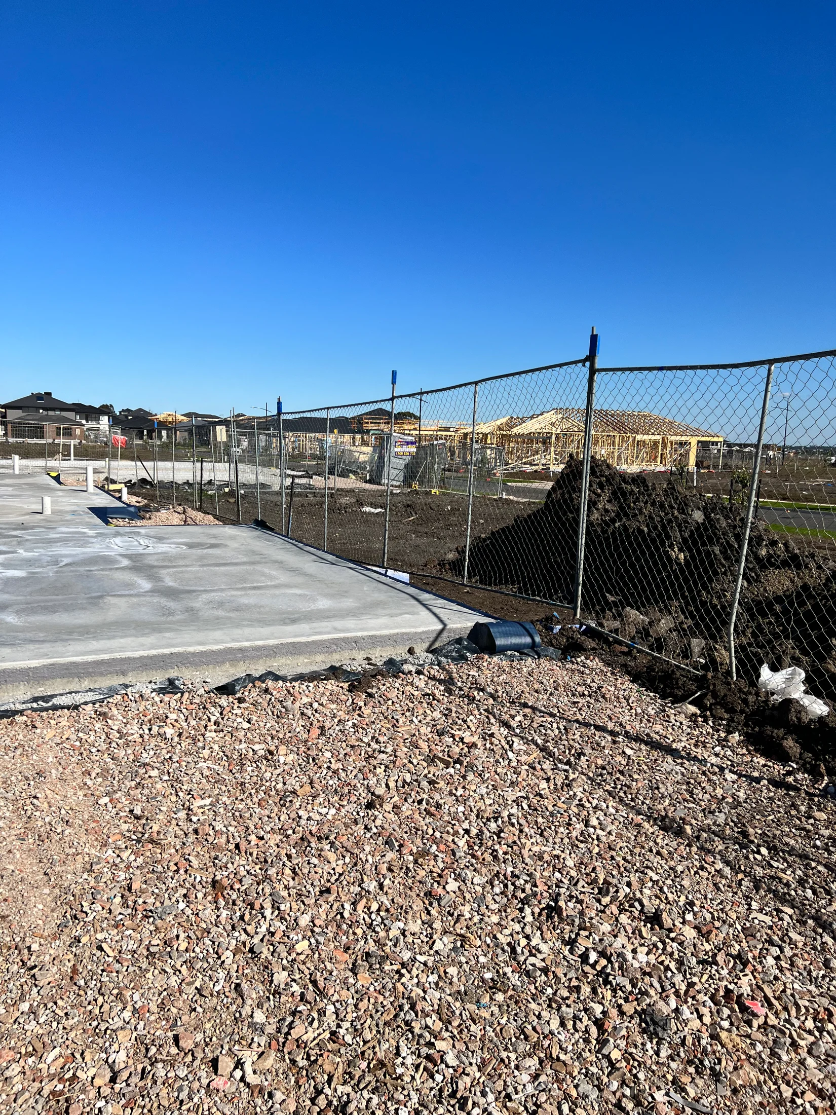 A slab of a new home build recently poured, and has been backfilled with crushed rock. Temporary fencing is in the photo.
