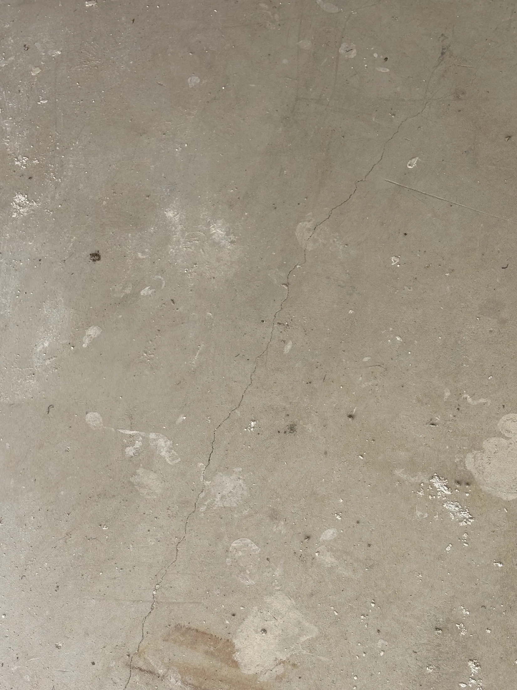 Cracked concrete floor with scattered white paint splatters. The surface has a rough texture and earthy tones, creating an aged appearance.