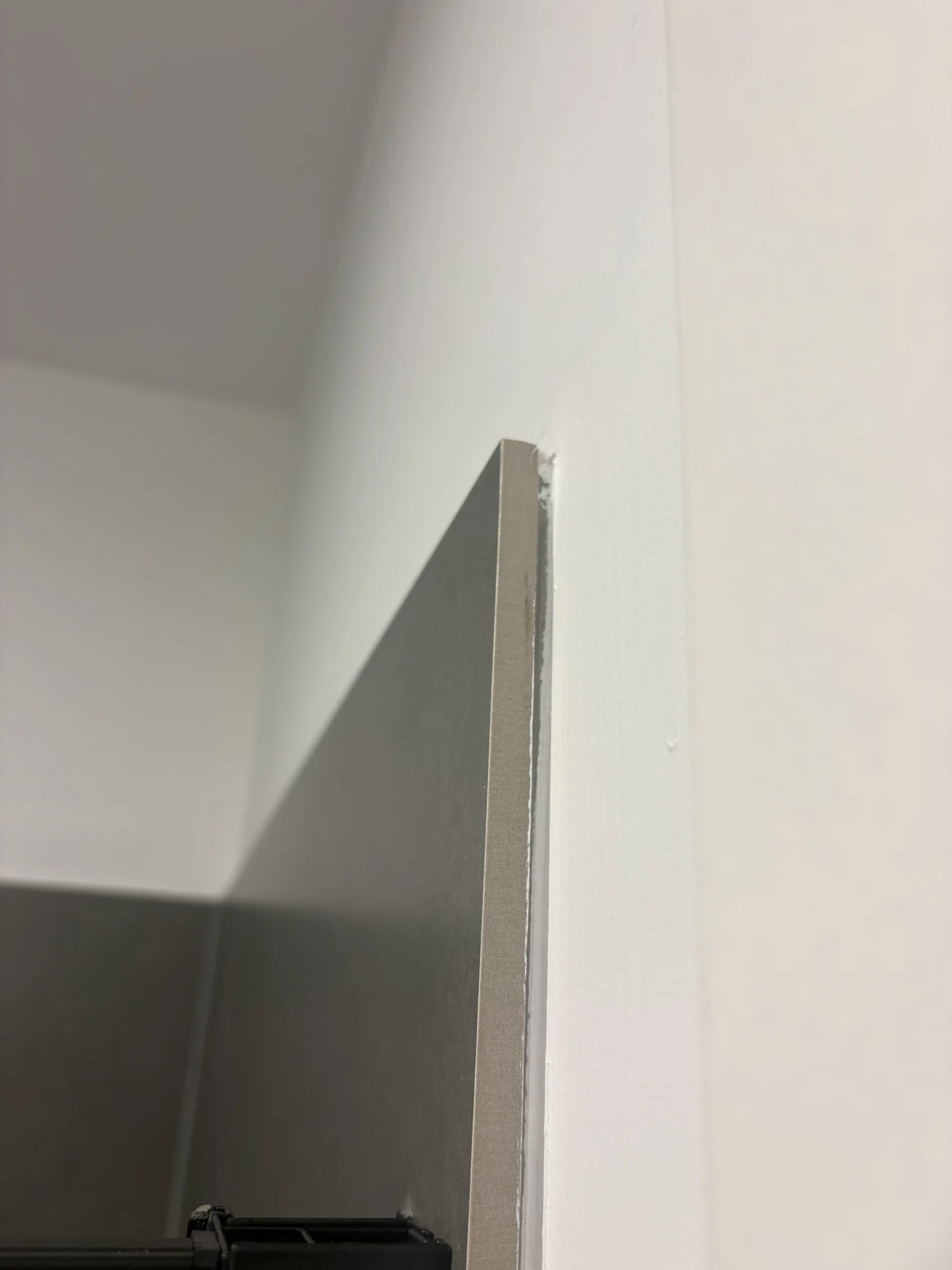 Close-up of a corner wall section, showing a gray panel adjacent to a white wall, highlighting clean lines and sharp edges.