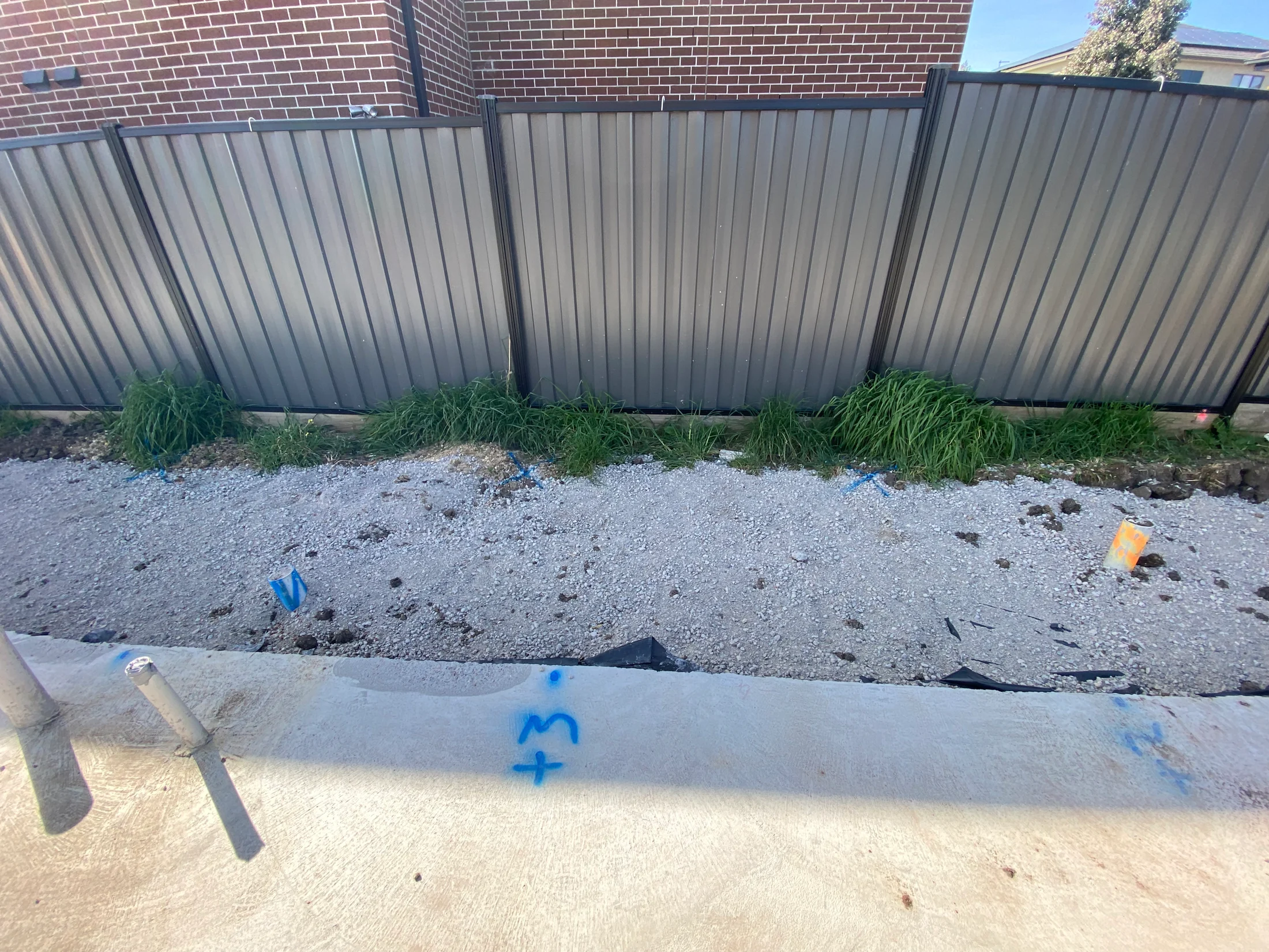 A concrete slab edge of new home build. Crushed rock and fence in background.