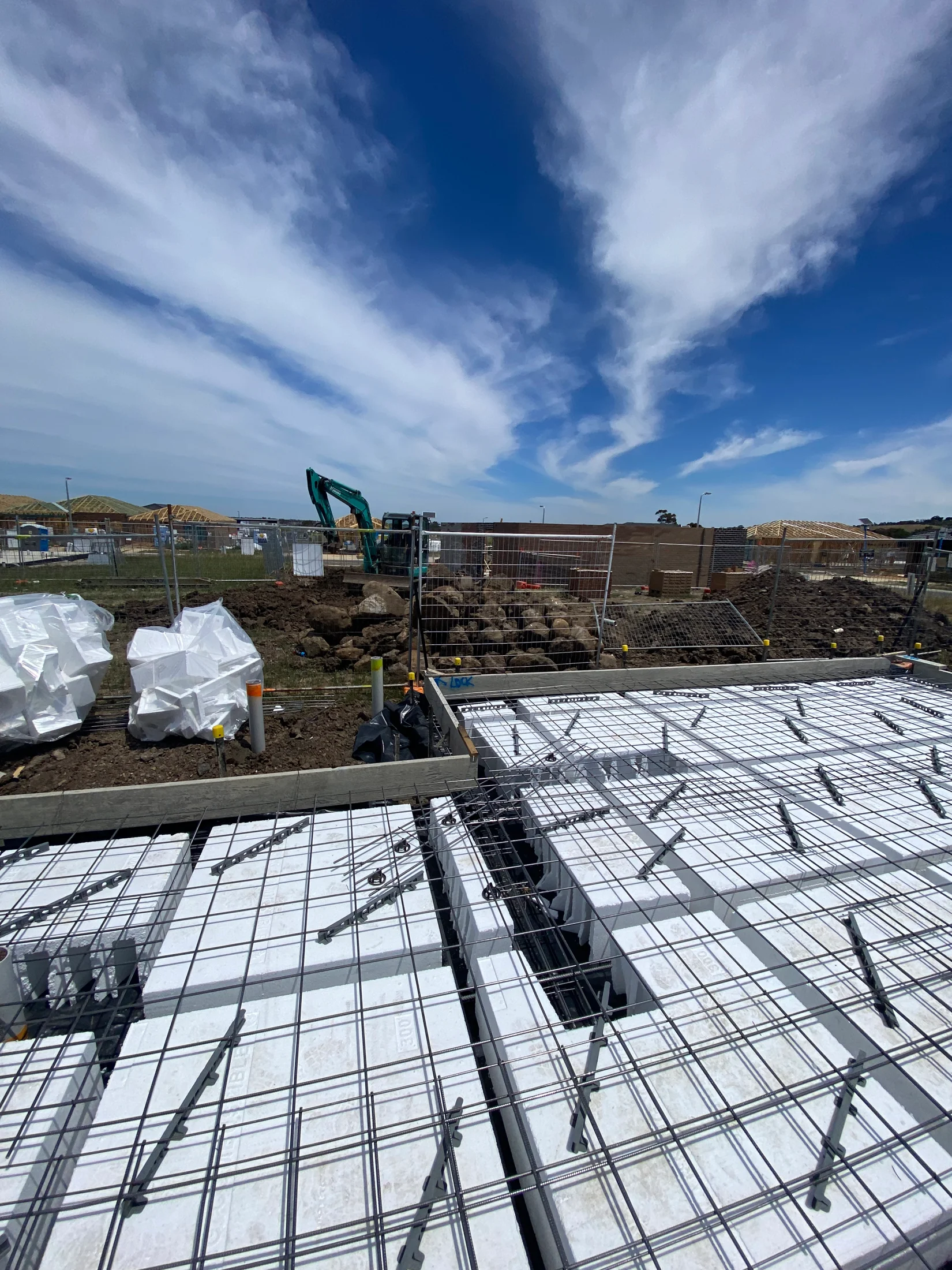 A concrete slab of a new home build set up, proper to pouring of the concrete with formwork, waffle pods, reinforcement and temporary fencing viewable.
