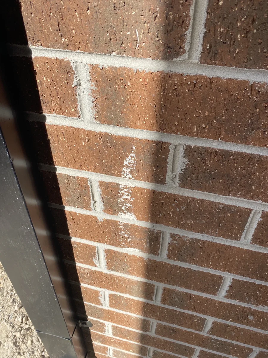 Red brick wall with gray mortar in sunlight, showing a vertical shadow on the left. No text or notable patterns visible.