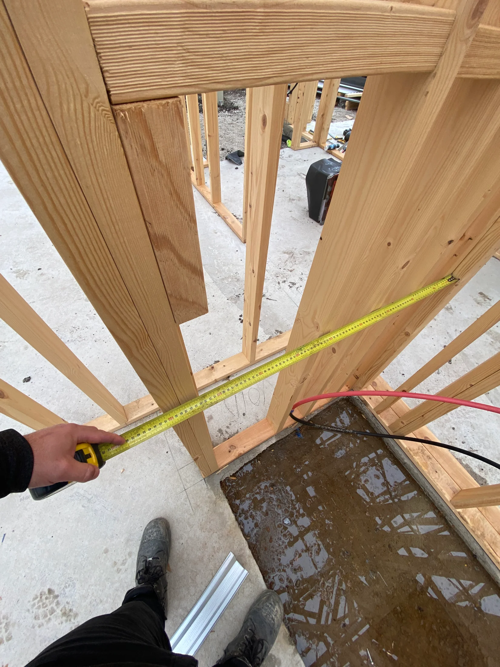 Inspector measuring the depth of a shower recess in new build at frame stage