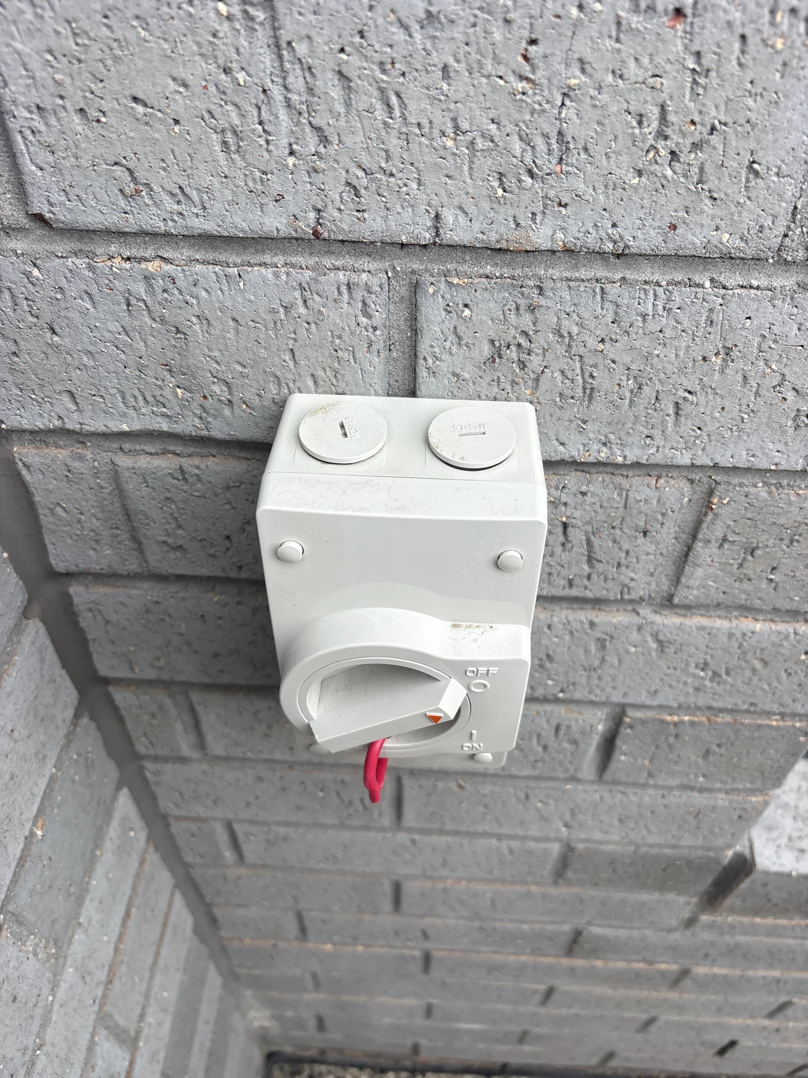 Gray wall with a white electrical switch box. The switch is set to "Off" and a red tag is attached. Text "Off" and "On" visible.